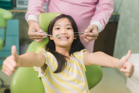 Portrait of happy asian girl shows thumb up gesture at dental clinicの写真素材