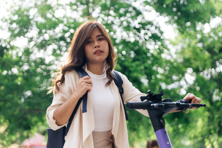 portrait of young asian woman riding electric scooter in parkの写真素材