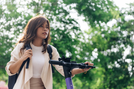 young asian woman in casual wear riding electric scooter in parkの写真素材