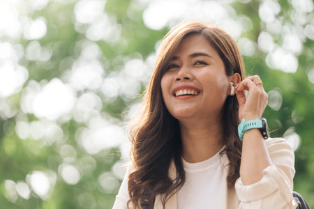 Portrait of happy young woman listening to music with wireless earphones outdoorsの写真素材