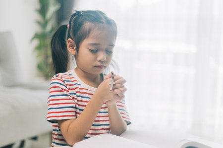 Asian little girl praying with rosary in hand at home.の写真素材