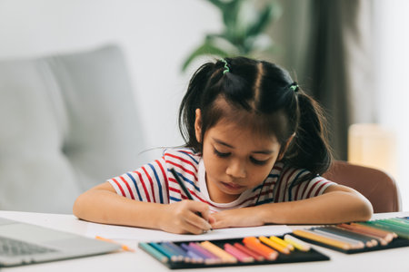 selective focus of cute asian child drawing with color pencils at homeの写真素材