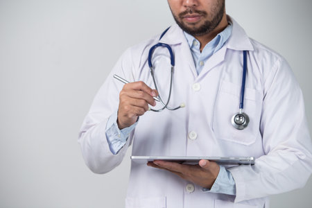 Cropped image of male doctor holding digital tablet while standing against white backgroundの写真素材