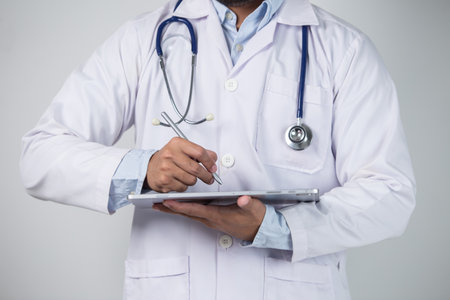 Close-up of a male doctor using digital tablet on grey backgroundの写真素材