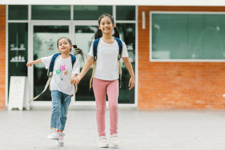 Two little girls with backpacks in the school.の写真素材