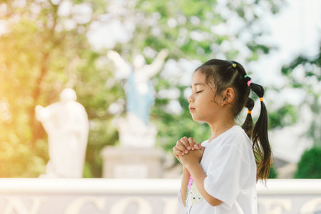 Little asian girl praying to God in the park. Religion concept.の写真素材
