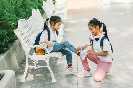 Two little girls sitting on the bench in the park and playing with soap bubblesの写真素材