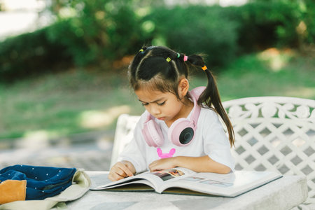 Cute little girl reading a book in the garden. Education concept.の写真素材