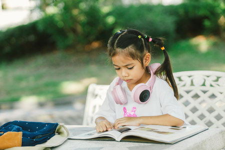 Little girl reading a book in the garden. Education and learning concept.の写真素材