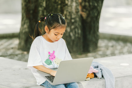 Little asian girl using laptop computer in the park, education conceptの写真素材