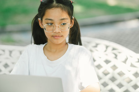Portrait of asian girl using laptop while sitting on the garden.の写真素材