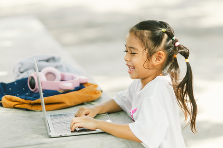 Cute little asian girl using laptop computer at outdoor park.の写真素材