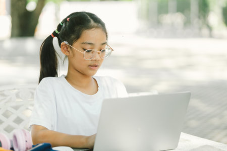 Portrait of young asian girl using laptop computer while sitting in the park.の写真素材