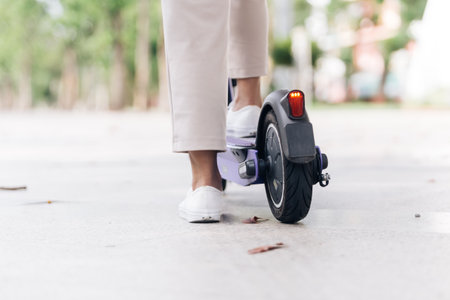 Close-up of woman legs in white sneakers riding electric scooter.の写真素材
