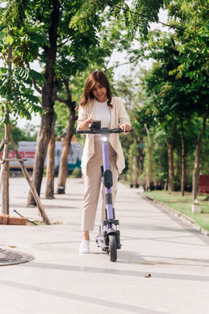 asian woman riding electric scooter in the park, lifestyle conceptの写真素材