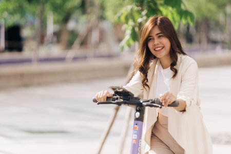 portrait of young asian woman riding electric scooter in parkの写真素材