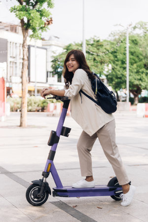portrait of young asian woman riding electric scooter in parkの写真素材
