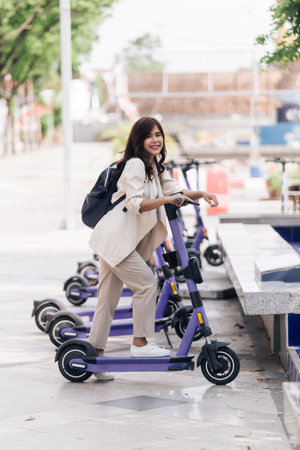 portrait of young asian woman riding electric scooter in parkの写真素材