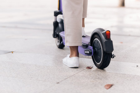 Close-up of woman legs riding electric scooter in the cityの写真素材