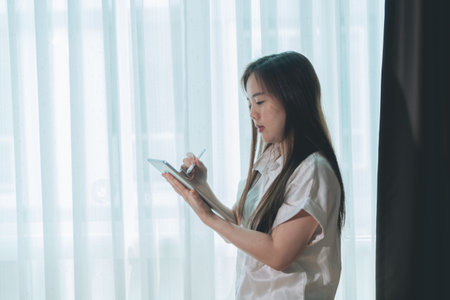 Asian woman using tablet pc in living room at home, business concept.の写真素材