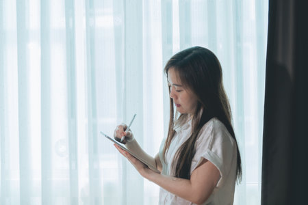 Asian woman using tablet pc in living room at home, business concept.の写真素材