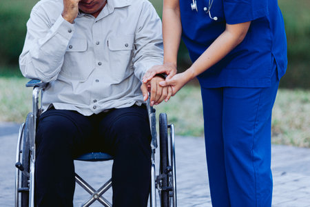 Nurse helping senior man on wheelchair in the park. Healthcare and medical concept.の写真素材
