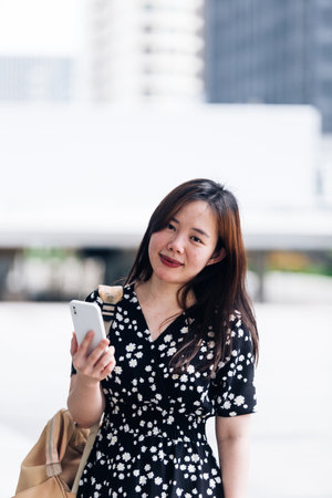 Portrait of a beautiful young asian woman using smartphone in the cityの写真素材
