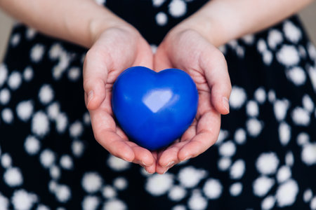 Blue heart in the hands of a woman in a polka dot dressの写真素材