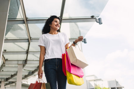 happy asian woman holding shopping bags in shopping mall, lifestyle concept