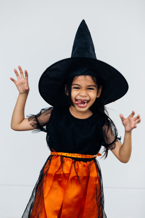 little girl in halloween costume with witch hat on white backgroundの写真素材