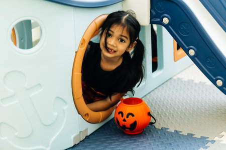 Little asian girl playing with halloween pumpkin in the playgroundの写真素材