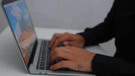A man is typing on a laptop with a mountain in the background