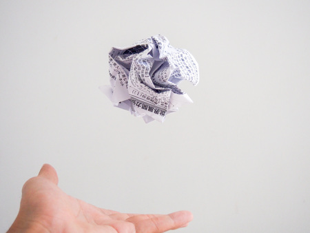 Isolated hand throwing a white paper ball with Japanese textの写真素材