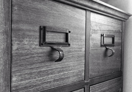 Rows of little drawers with white empty tags in an old furniture moduleの素材