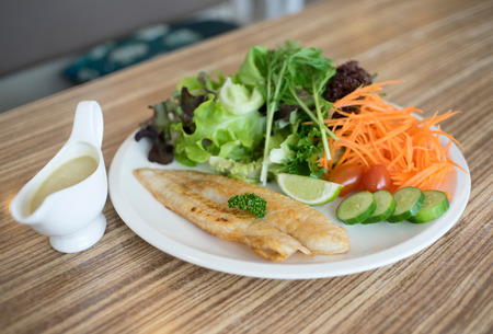 Fish dish - fried fish fillet with vegetables on tableの写真素材