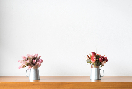Decorative artificial flowers in a vase on a wooden table.の写真素材
