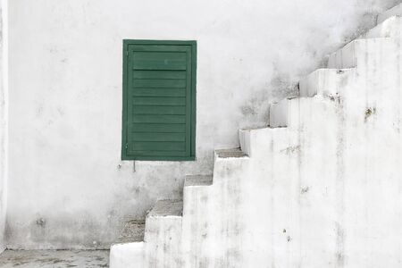 The old white staircase with green window.の写真素材
