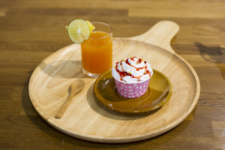 orange juice with cupcake on wooden tray on wooden tableの写真素材