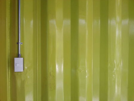 Metal wall yellow color texture with light switchの写真素材