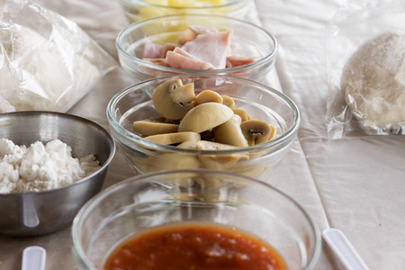 Pizza ingredient with mushroom ham pineapple dough and sauce on pink tableの写真素材