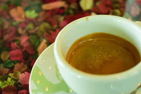 Coffee in white cup on table with flowerの写真素材