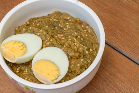 Thai food pound eggplant with boiled egg in white cup on wood table