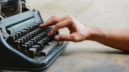 Vintage typewriter and human hand on a wood tableの写真素材