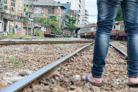 Man with jeans and slippers standing on railroad track