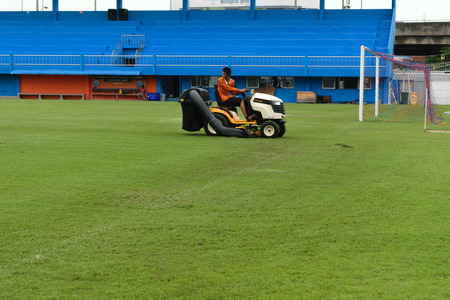 Bangkok, Thailand - September 15, 2015 : Unidentified man mowing the grass on a football stadium at PAT Stadium. PAT Stadium is a stadium in the Khlong Toei district Bangkok, Thailand.のeditorial素材