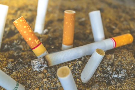 Cigarette burning in outdoors ashtray with sand closeup , process in vintage styleの写真素材