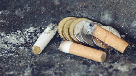 Thai coin and cigarette burning in outdoors ashtray , process in vintage styleの写真素材