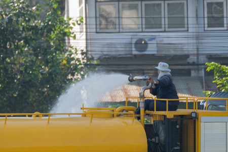 Bangkok, Thailand - November 21, 2015 : Unidentified Bangkok Metropolitan Administration worker working for watering the lawn on road by water tanker truck in Bangkok, Thailand.のeditorial素材