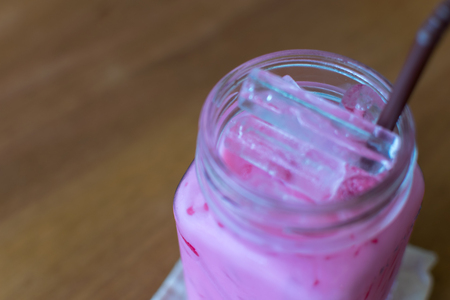 Milk pink sweet cold drink in glass on a wood tableの写真素材