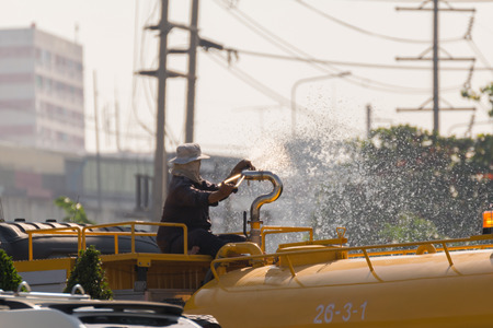 Bangkok, Thailand - November 21, 2015 : Unidentified Bangkok Metropolitan Administration worker working for watering the lawn on road by water tanker truck in Bangkok, Thailand.のeditorial素材